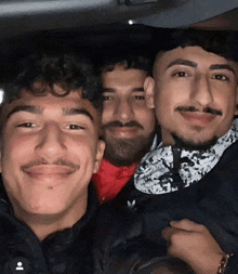 three men are posing for a picture with one wearing an adidas shirt