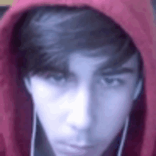 a close up of a young man wearing a red hoodie and earbuds .