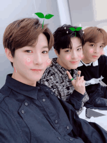 three young men are posing for a picture and one of them has a plant on his head