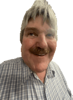 a man with gray hair and a mustache wearing a plaid shirt smiles for the camera