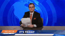 a man in a suit and tie is holding a piece of paper in front of a news desk that says it 's friday