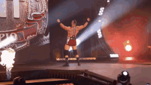 a wrestler stands on a stage with his arms outstretched in front of a sign that says ' championship '