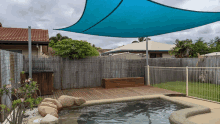 a blue umbrella is over a swimming pool in a backyard