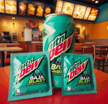 a can of mtn dew baja blast sits on a table next to three packets