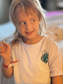 a little girl wearing a white t-shirt that says " a leaf in yours "