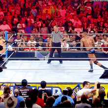 a referee stands in the middle of a wrestling ring in front of a crowd that is watching a match