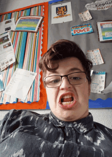 a boy making a funny face in front of a bulletin board with a sign that says knowledge is power