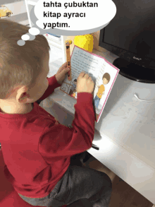 a little boy is reading a book with a thought bubble that says tahta çubuktan kitap ayraci yaptim