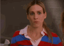 a woman in a red and blue striped shirt is looking at the camera