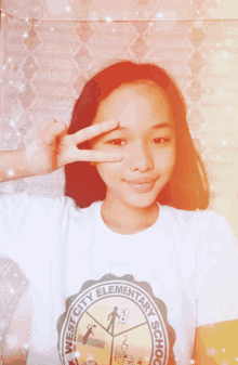 a girl wearing a west city elementary school shirt giving the peace sign