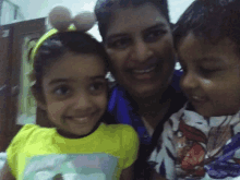 a woman and two children are posing for a picture and the little girl is wearing a yellow shirt