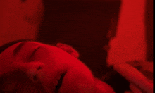 a close up of a person 's face with their eyes closed in a red light