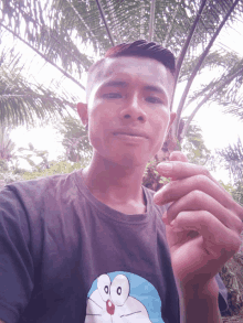 a man wearing a doraemon shirt holds a cigarette in his hand