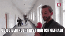 a man is holding a microphone in a hallway and says ob du behindert bist hab ich gefagt