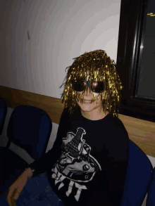 a young boy wearing a wig and sunglasses is wearing a black shirt with a guitar on it