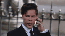 a man in a suit talking on a cell phone