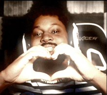 a man is making a heart shape with his hands in front of a acer chair