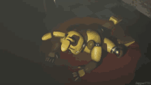 a yellow robot is laying on its back on a red carpet in a dark room