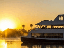 a boat is floating on a body of water at sunset with the sun setting behind it .