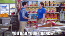 a man and a woman are standing in a grocery store and the woman is holding a bag of chips .