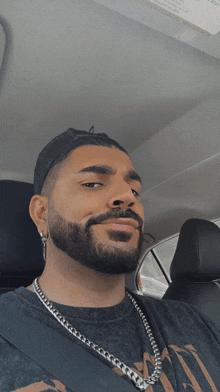 a man with a beard is sitting in a car with a seat belt on