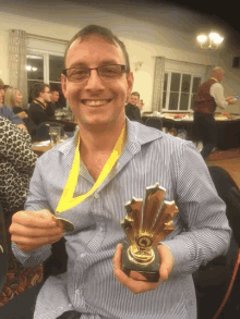 a man wearing glasses and a medal around his neck holds a trophy