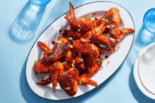 a plate of chicken wings with green onions on a table