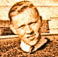 a close up of a man 's face with a brick wall in the background