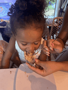 a little girl is eating ice cream with a toothpick