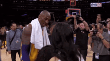 a basketball player with a towel around his neck talks to a woman in front of a scoreboard that says fox sports