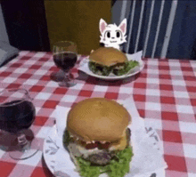 two hamburgers and a glass of wine are on a checkered tablecloth .