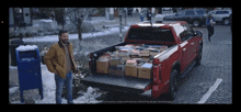 a man stands in front of a red truck with a mailbox in the snow