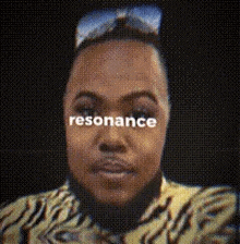 a man wearing sunglasses and a tiger print shirt with the word resonance written on his face .