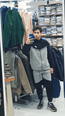 a man is taking a selfie in front of a mirror in a clothing store