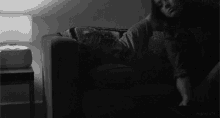 a woman is laying on a couch in a dark room with a lamp .