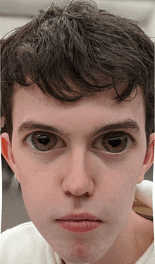 a close up of a young man 's face with a large eye