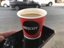 a cup of nescafe coffee is sitting on a phone