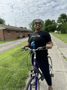 a woman wearing a black shirt that says good day is riding a purple bike