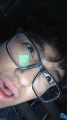 a close up of a person wearing glasses with a green object in their eye