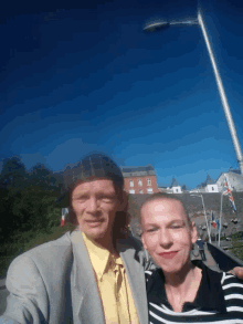 a man in a suit and a woman in a striped shirt pose for a photo