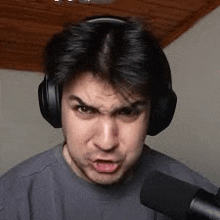 a man wearing headphones and a microphone is making a face .