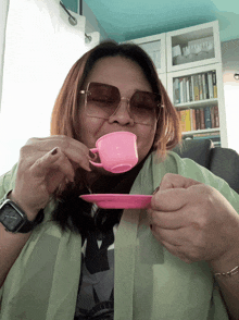 a woman wearing sunglasses drinks from a pink cup