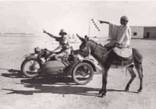 a black and white photo of a man riding a donkey next to a motorcycle .