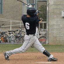 a baseball player with the number 6 on his back is swinging at a pitch .