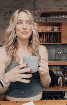 a woman in a kitchen holds a cup of coffee