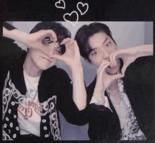 two men are making a heart shape with their hands in front of their faces .