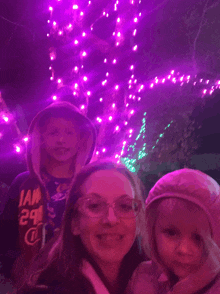 a woman wearing a hoodie that says iam 29 stands next to two children