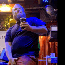 a man in a black shirt is holding a glass of beer in front of a sign that says yo