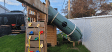 a green slide is attached to a wooden structure