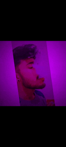 a man with a beard is smoking a cigarette in a purple room .